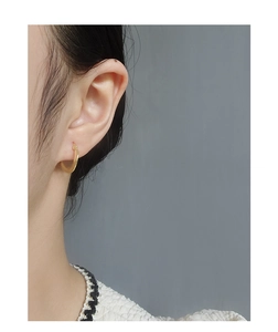 Close-up of polished gold hoop earrings worn by a model for a minimalist fashion look