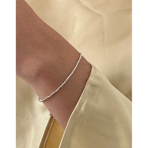 Minimalist S925 sterling silver beaded bracelet on model wrist with shimmering finish