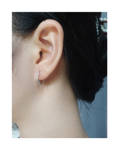 Close-up of small polished S925 sterling silver geometric hoop earring worn on ear