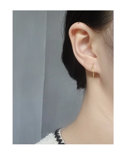 Close-up of minimalist gold geometric hoop earring worn on a female earlobe model