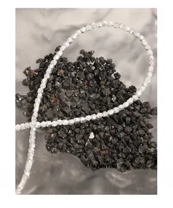 Detailed view of multifaceted irregular silver beads on textured black stone background