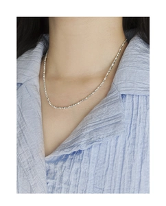 Detail of shimmering silver crushed bead necklace worn on a woman's collarbone