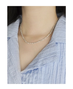 Macro shot of minimalist polished S925 sterling silver beaded chain on female collarbone