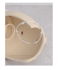 Detail view of a minimalist S925 sterling silver beaded bangle on geometric stone background