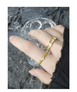 Close-up of gold beaded ring and hollow band with cubic zirconia worn by model
