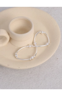 Detail of silver S925 beaded bracelet with smooth metal tubes on a ceramic tray