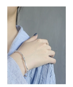 Close-up of minimalist S925 sterling silver beaded bracelet worn on a model wrist