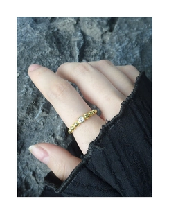 Close-up of golden beaded ring with a single round zircon on a minimalist model's hand