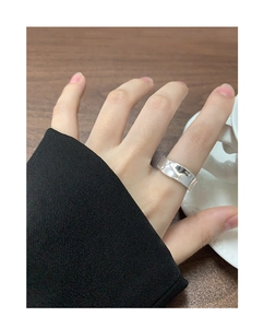 Gros plan d'une bague large en argent S925 avec texture ondulée portée par une femme