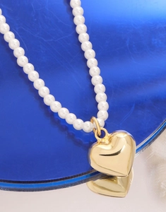 Vue détaillée du pendentif cœur en argent S925 sur un collier de perles blanches dorées