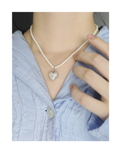 Détail du pendentif cœur en argent S925 sur collier de perles blanches sur modèle
