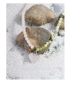 Close-up of pearl and green stone necklace with a polished silver heart pendant