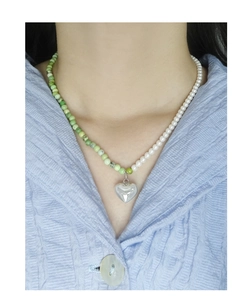 Detail of silver heart pendant with green jade beads and white pearls on necklace