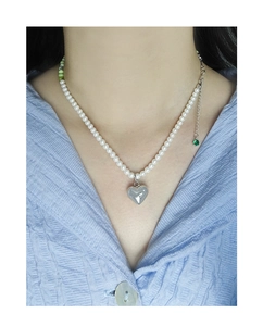 Detail of S925 silver heart pendant on a pearl necklace with green accent beads