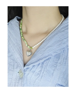 Close-up of S925 silver heart necklace with white pearls and green stones on a model