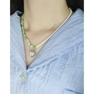 S925 silver necklace with white pearls, green beads and heart pendant on a model