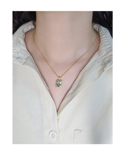 Details einer goldenen Halskette mit rechteckigem Anhänger und blauem Edelstein