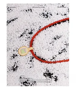 Macro detail of red agate beaded necklace with gold M initial enamel pendant