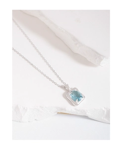 Makroaufnahme der S925 Silberhalskette mit blauem Edelstein auf weißem Marmorstein