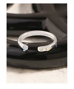 Vue macro d'une bague en argent S925 avec zircons bleus et jaunes sur support noir