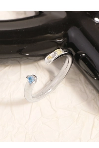 Vue latérale macro de la bague ouverte argentée avec pierres zircons bleues et jaunes