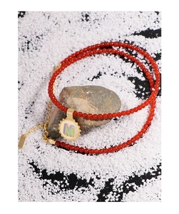 Detailed close-up of red agate beaded necklace with gold letter M sunburst pendant