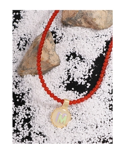 Macro detail of red carnelian beaded necklace with gold enamel letter M charm