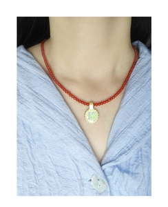 Detail of red agate beaded necklace with gold plated letter M disc pendant on model