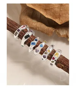 Macro shot of vintage S925 silver rings with colorful zircon gemstones on a wooden branch