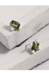 Makroaufnahme von Silberohrstecker mit olivgrünem Zirkon auf einer Steinoberfläche