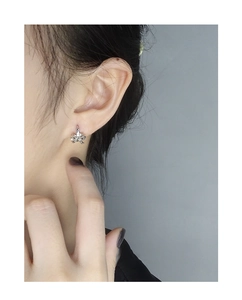 Close-up of minimalist silver bow earrings on model ear with polished metallic finish