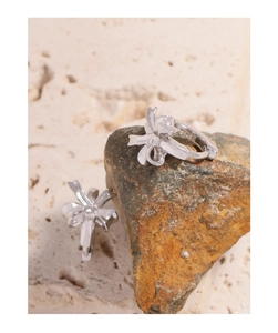 Macro detail of S925 sterling silver bow knot hoop earrings on textured stone