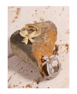 Close-up of S925 hallmark on gold and silver bow hoop earrings atop natural stones