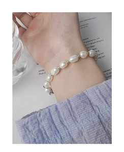 Minimalist baroque pearl bracelet with silver beads on a model's wrist with soft background