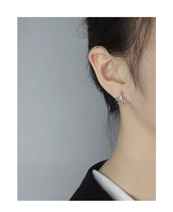 Close-up of minimalist silver bow earrings worn by a model in a modern style