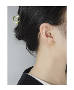Close-up of elegant gold bow earrings and a minimalist round hair clip on a model
