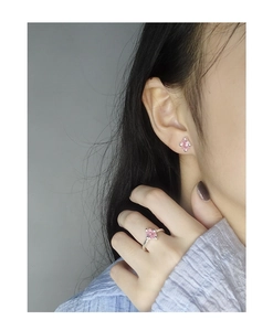 Detailansicht zierlicher rosa Zirkon-Ohrringe und offener Ring an einem Modell