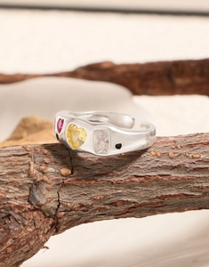 Detail of S925 silver open ring with red and yellow heart zircons on a rustic branch