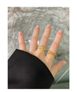 Detailed view of two gold rings with star engraving and layered bead textures on fingers
