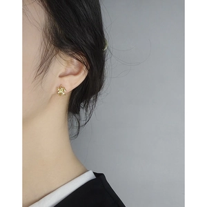 Minimalist S925 sterling silver bow earrings in gold, worn by a model on a grey background