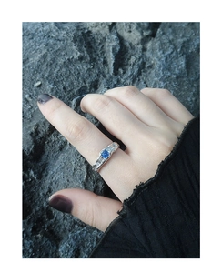 Macro shot of silver ring with blue zircon and textured band on model finger