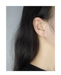 Gros plan d'une puce d'oreille minimaliste en argent S925 avec opale irisée sur l'oreille