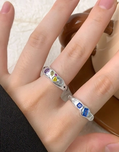 Detail of silver S925 rings with colorful zircons and star engraving on a cozy background