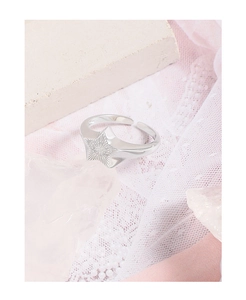Macro shot of silver star ring detail with radiant textured patterns on lace background