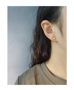 Close-up of minimalist gold-tone zircon stud earrings worn on the earlobe for daily look