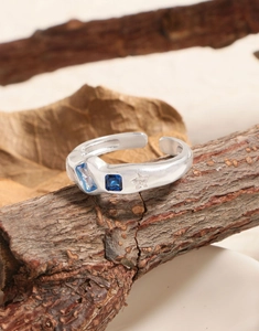Detail of S925 silver ring with blue zircons and star engraving on bark texture