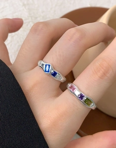 Macro shot of S925 silver rings with colorful rectangular gemstones on a wooden tray