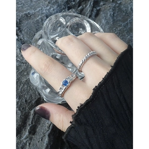 Minimalist S925 silver rings set with blue zircon and textured lava finish on a grey rock