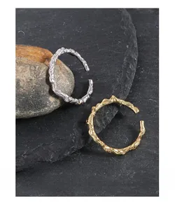 Macro shot of gold and silver open rings with irregular molten lava fluid texture on rocks