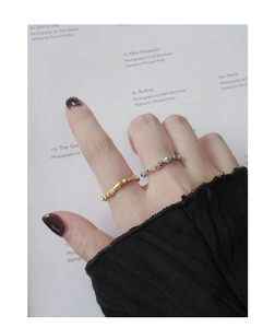 Close-up of gold and silver liquid metal rings with irregular lava texture on hand